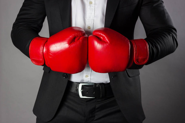 Businessman in red boxing gloves isolated in front of grey backg - Fotografie, Obrázek
