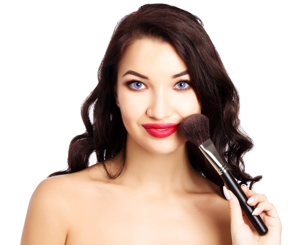 Mooi meisje met een make-up borstel, geïsoleerd op witte achtergrond - Foto, afbeelding