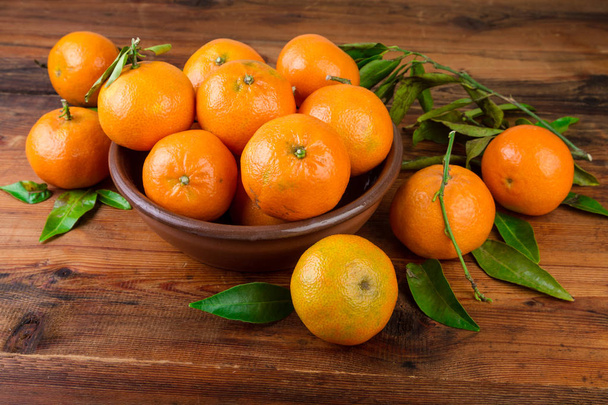 Mandarijnen tangerines in bruin keramiek kom  - Foto, afbeelding