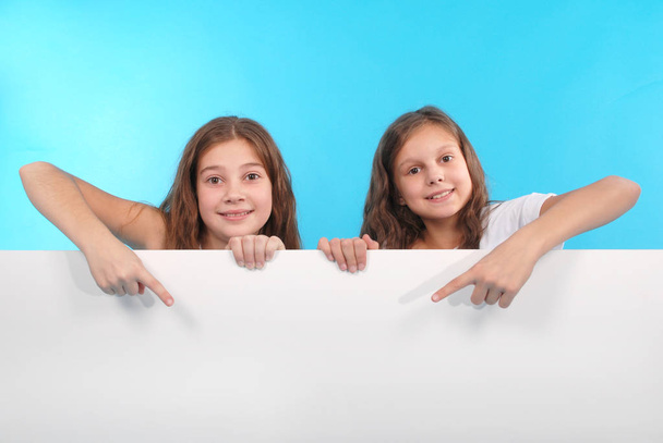 zwei glücklich lächelnde schöne junge Mädchen, die leeres Schild oder Kopierraum für Slogan oder Text zeigen - Foto, Bild