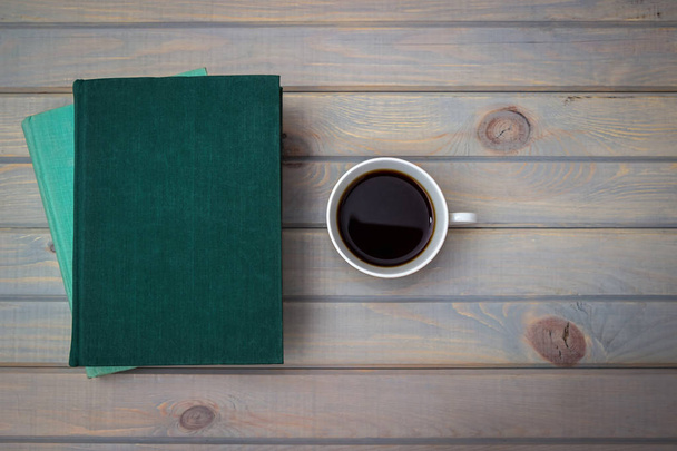 Green and blue books with a white porcelain cup of coffee on a gray wooden background. - Foto, Imagem