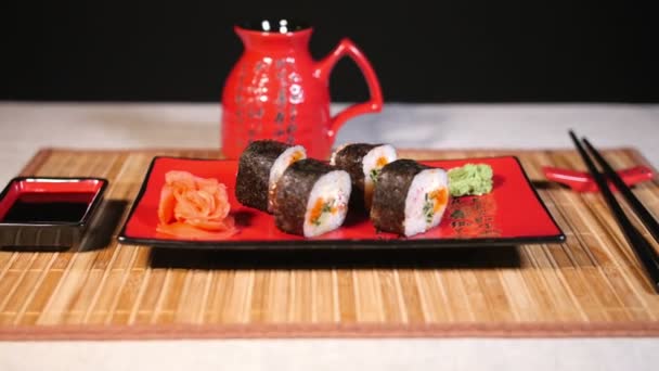 Japanilainen sushi punaisella levyllä syömäpuikoilla bambu taustalla
 - Materiaali, video