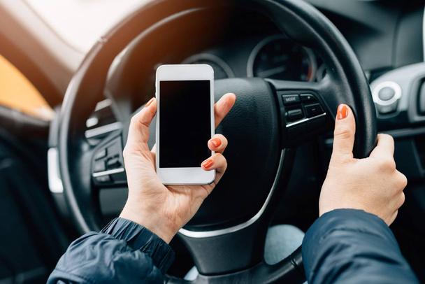 Woman using white smartphone in car. - Foto, immagini