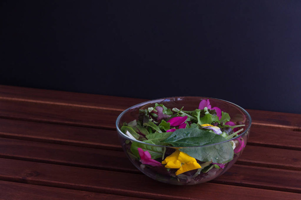 Glass bowl filled with organic superfood salad with flowers with lemon juice. - Фото, зображення