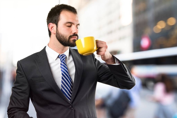 Jovem empresário bebendo um café sobre fundo branco
 - Foto, Imagem