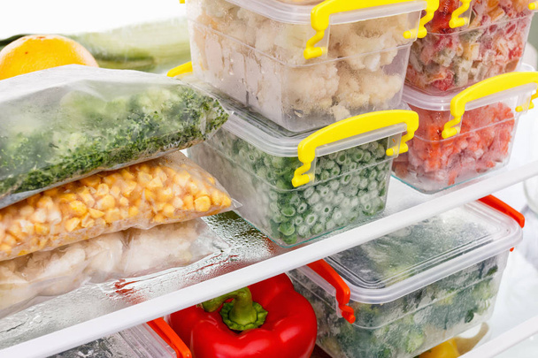 Frozen food in the refrigerator. Vegetables on the freezer shelves. - Photo, image