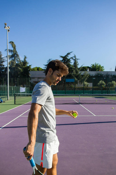 Профессиональный теннисист играет в теннис на теннисном корте солнечным летним утром. Он одет в спортивную одежду.
. - Фото, изображение