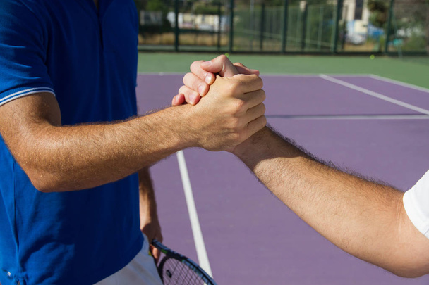 Двое мужчин, профессиональные теннисисты, пожимают руку до и после теннисного матча
. - Фото, изображение
