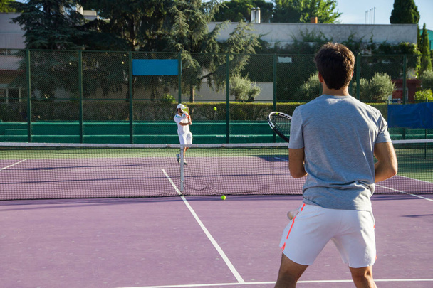 Jugador de tenis profesional jugando el juego en la cancha de tenis. Le da la espalda a la cámara.
. - Foto, imagen