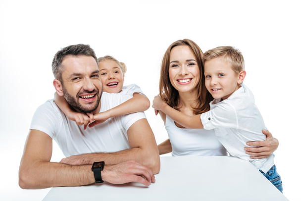 Lachende gezin in witte t-shirts knuffelen  - Foto, afbeelding