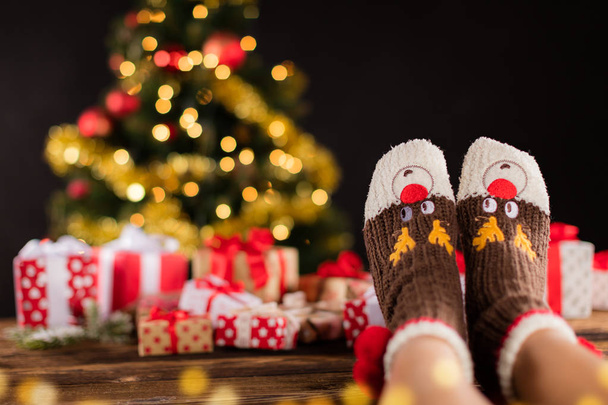 Woman feet in woollen socks, blur Christmas background - Foto, afbeelding
