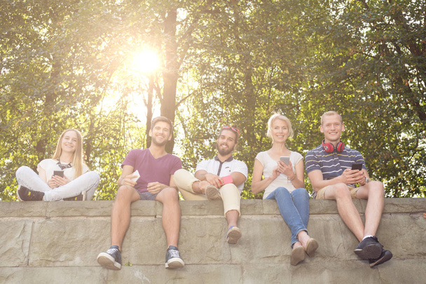 People sitting on park wall - Photo, image