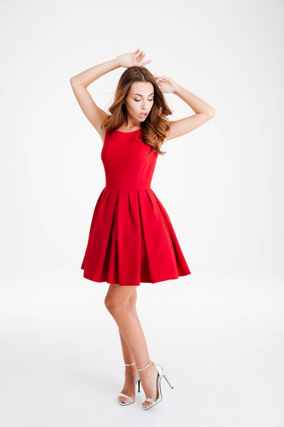 Pretty brunette woman in red dress posing with raised hands - Foto, Imagem