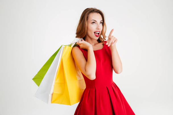 Charming attractive woman in red dress holding shopping bags - Фото, зображення