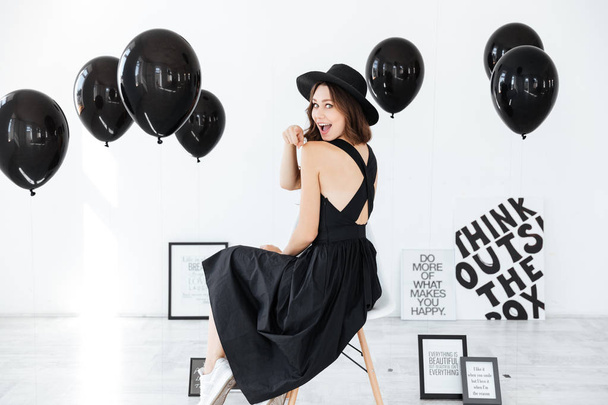 Woman sitting with black balloons and posters over white background - Photo, Image