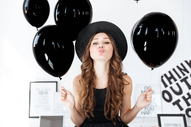 niedliche Frau mit schwarzen Luftballons und Plakaten, die einen Kuss senden - Foto, Bild