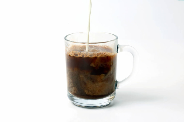 milk poured into a transparent cup of black coffee - Photo, Image