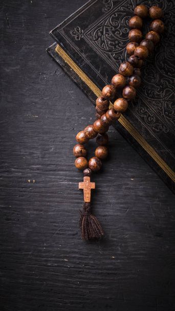 Rosary on the Bible on a wooden background. Holy book. - 写真・画像