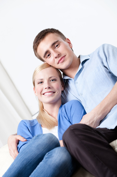 Happy couple sits on the white leather sofa - Foto, Imagen