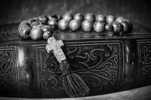 Rosary on the Bible on a wooden background. Holy book. Black and white photography - Photo, Image