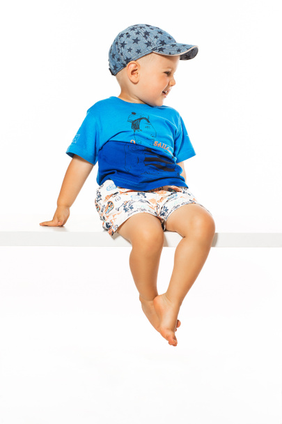 Blond boy sitting on the table, white background - Foto, afbeelding