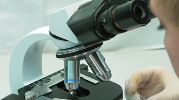 Γυναίκα γιατρό επιστήμονας αναζητούν μέσα από το μικροσκόπιο - Πλάνα, βίντεο