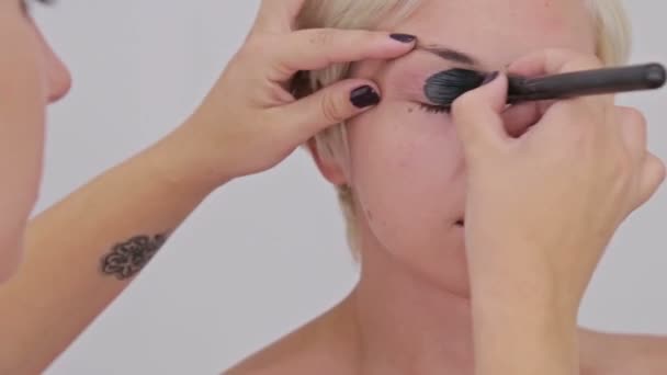Professional make-up artist applying cream base eyeshadow primer to model eye - Footage, Video