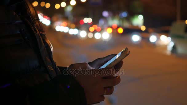 Az ember sms textil app alkalmazással smartphone éjszakai város, télen. - Felvétel, videó