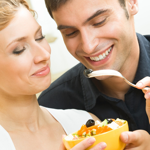 Cheerful young couple with vegetarian salad at home - Фото, изображение
