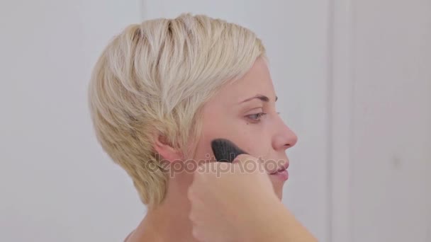 Z bliska strzał. Make-up artist stosowania makijażu na twarzy zmysłowe model - Materiał filmowy, wideo