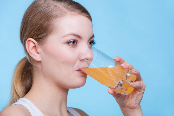 Woman drinking orange flavored drink or juice - Foto, afbeelding