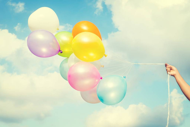 Woman hand holding colorful balloons on blue sky  - Foto, imagen