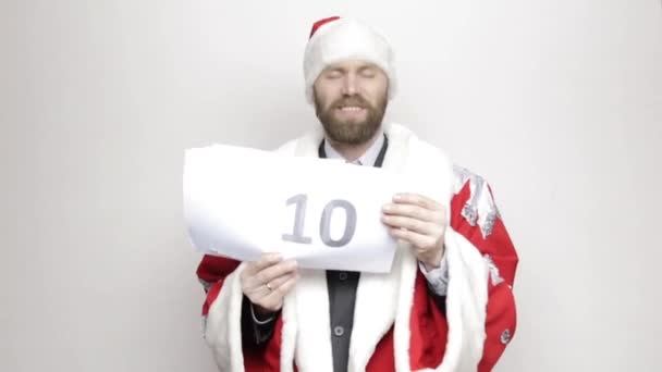 businessman in a suit of Santa Claus holds a sheet of paper with numbers. final countdown - Felvétel, videó