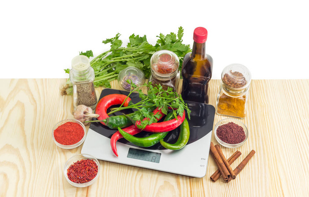 Чили на кухонном весе и различные специи, травы и соус
 - Фото, изображение