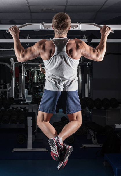 very power athletic guy, execute exercise tightening on horizont - Фото, изображение