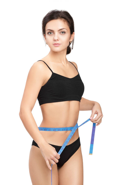 woman measuring her waist by blue measure tape - Φωτογραφία, εικόνα