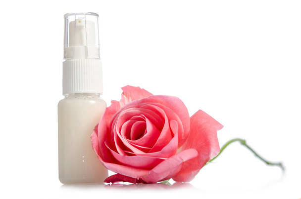 Face cream bottle with pink rose isolated on white - Fotó, kép