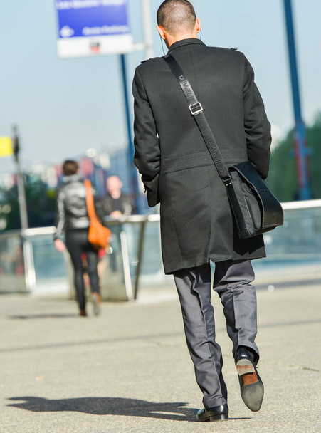 La defense, France- April 10, 2014: back view of businessman walking in a street.He wears shoulder strap bag - Photo, Image