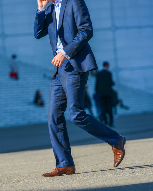 La defense, France- April 09, 2014: side view of businessman walking in a street. He wears a very elegant blue suit and high quality city shoes - Fotó, kép