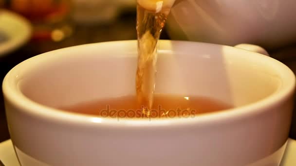 Fekete tea özönlenek a csésze, teáskanna és keverjük - Felvétel, videó