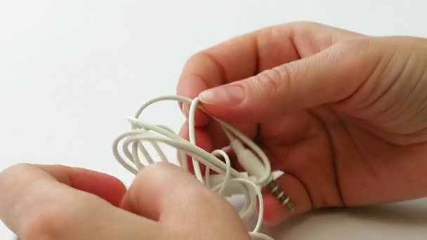 Frau entwirrt verworrene Ohrhörer oder Ohrhörerknoten - Filmmaterial, Video