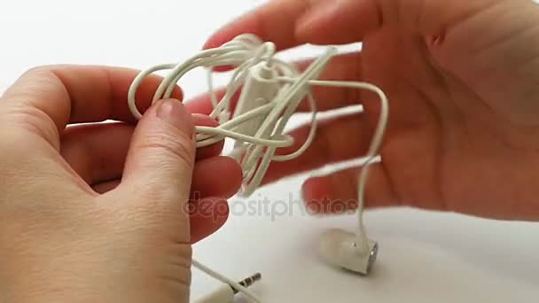 Žena untangles zamotaný sluchátka nebo sluchátka uzel - Záběry, video