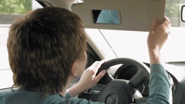 Mujer corrige el maquillaje en un espejo de la visera del sol del coche
 - Metraje, vídeo