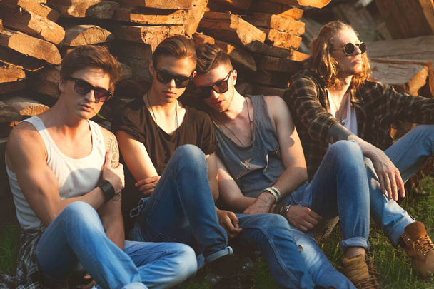 fashion guys friends sitting on the grass, wood backgrounds, sun - Foto, Imagem