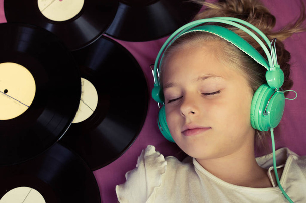 Красива дівчина лежить поруч з вініловими записами і слухає музику на навушниках
. - Фото, зображення