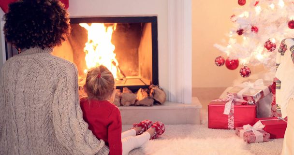 Mother and child warm up by the fireplace - Photo, Image