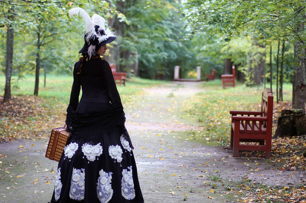 ragazza in abito retrò XVIII secolo con valise in parco
 - Foto, immagini