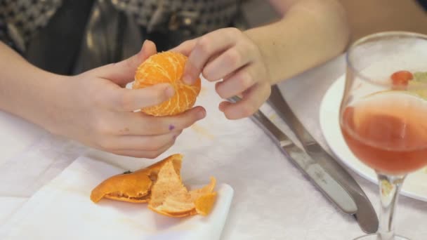 Woman peeling a mandarine indoors - Záběry, video
