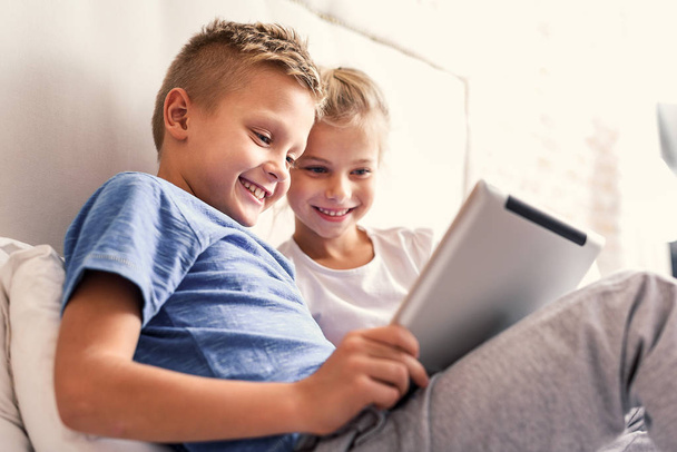 Children enjoying digital gadget in bedroom - Фото, зображення