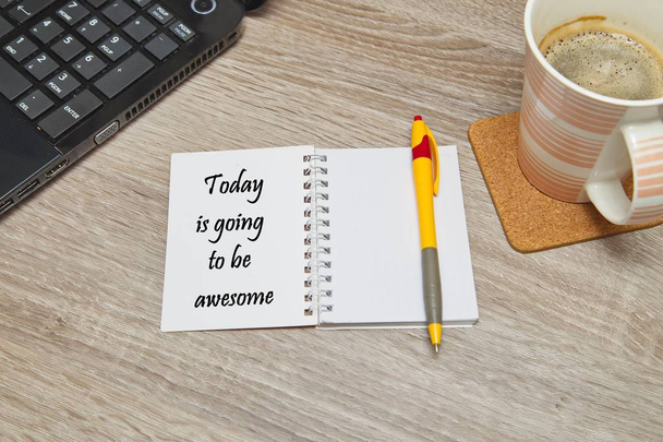 Open notebook with text  "Today is going to be awesome" and a cup of coffee on wooden background. Top down view - Foto, imagen